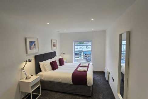 Modern bedroom with a large bed, stylish decor, and natural light. Perfect for comfortable stays in.