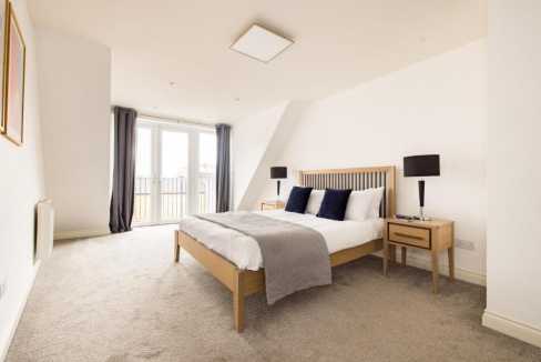 Bright bedroom in Staines-upon-Thames High St apartments with large windows and contemporary furnish.