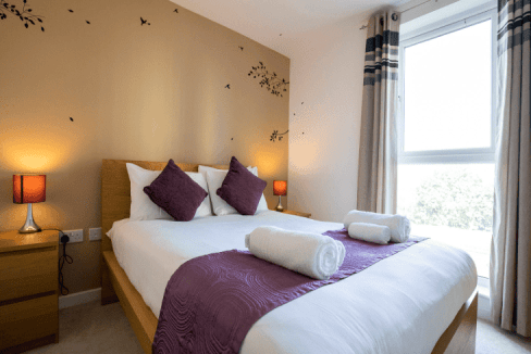 Comfortable bedroom at Woking York Road Apartments with stylish decor and ample sunlight.