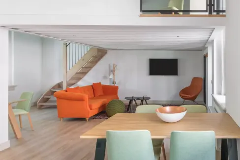 Bright interior of a modern living space with orange sofa and minimalist decor in Amsterdam Wittenbe.