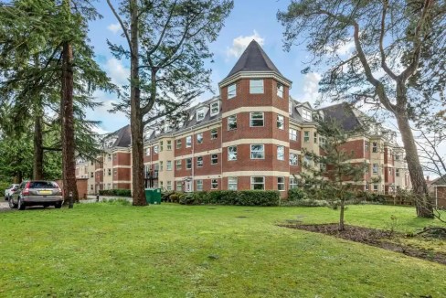 Modern apartment building at Camberley Station with lush green surroundings.