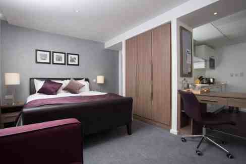 Modern Birmingham Martineau Place Aparthotel bedroom with stylish decor and workspace.