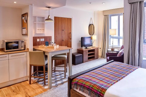 Modern hotel room at Royal Albert Docks Aparthotel with cozy furnishings and city views.