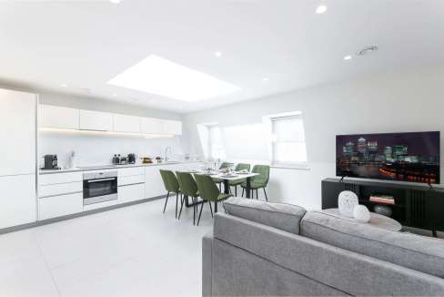 Bright open-plan living area in a Marylebone London penthouse with sleek white kitchen and contempor.