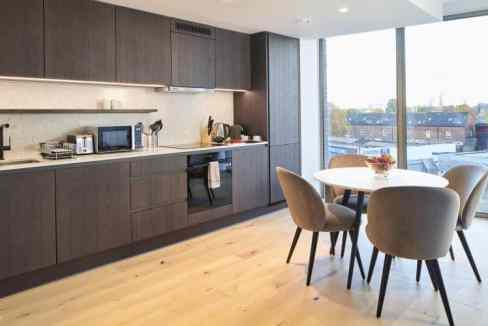 Modern kitchen with sleek dark cabinetry and large windows in King's Cross apartments.