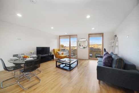 Spacious living area featuring contemporary furniture and large windows with city views.