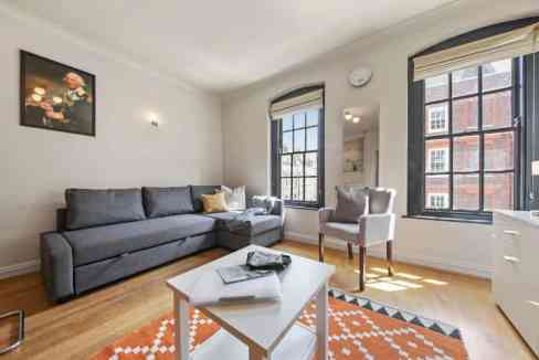 Bright living room in Liverpool Street Station apartments with large windows and contemporary furnit.