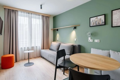 Comfortable living space at Munich train station aparthotel featuring a sofa, dining area, and natur.