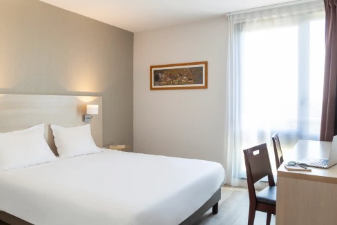 Modern hotel room with a large bed, desk, and window at Avignon TGV Aparthotel.
