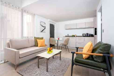 Bright living room with sofa, armchair, and open kitchen in York City Centre.