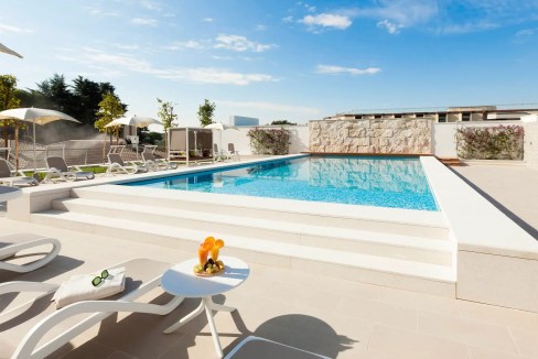 Rooftop pool at Rome Balduina Aparthotel with sun loungers and cityscape views.