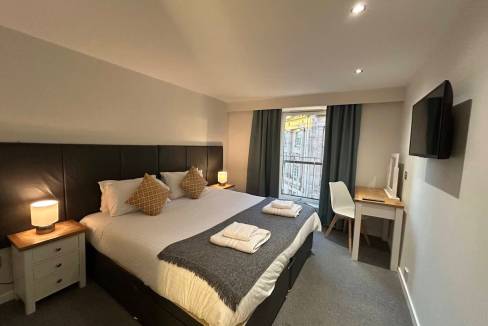 Modern Glasgow Gallowgate Apartments bedroom with cozy decor and city view.