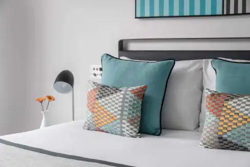 Stylish hotel bedroom with decorative pillows and contemporary design.
