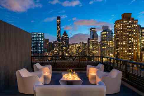 Rooftop lounge with city skyline view at East River Residences, featuring modern seating and ambient.