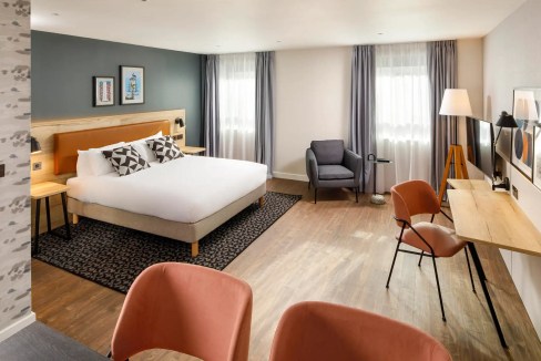 Spacious hotel room at Sutton Train Station Aparthotel with stylish decor and comfortable furnishing.