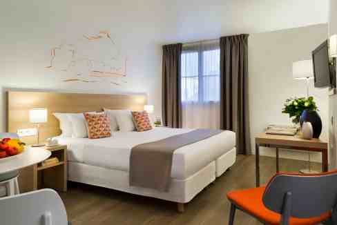 Modern hotel room at Lyon Bellecour Aparthotel with comfortable bed and stylish decor.