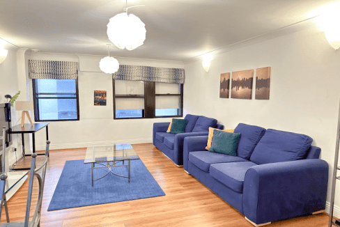 Comfortable living room with blue sofas and large windows in Monument Serviced Apartments.