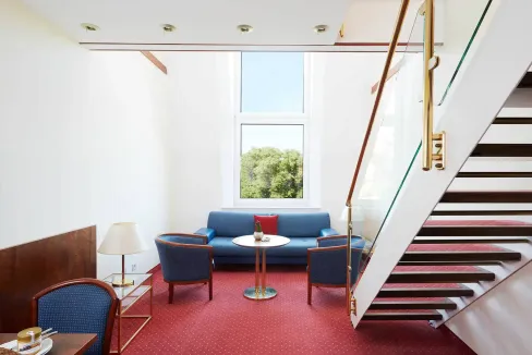 Modern lounge with blue sofa and chairs at Berlin Weissensee Aparthotel, bright natural light.