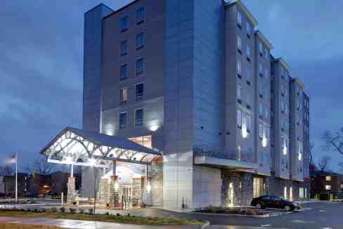 Modern Ohio University Aparthotel building at dusk with illuminated entrance.