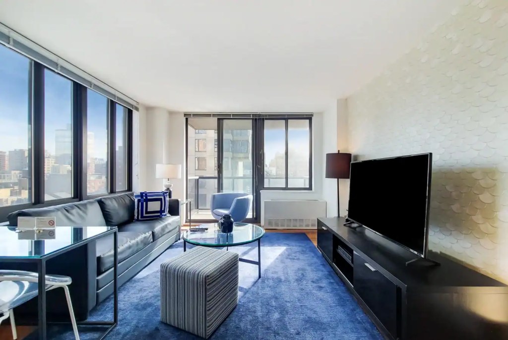 Spacious living room with large windows, contemporary furniture, and cityscape views at Gramercy Par.