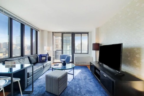 Spacious living room with large windows, contemporary furniture, and cityscape views at Gramercy Par.