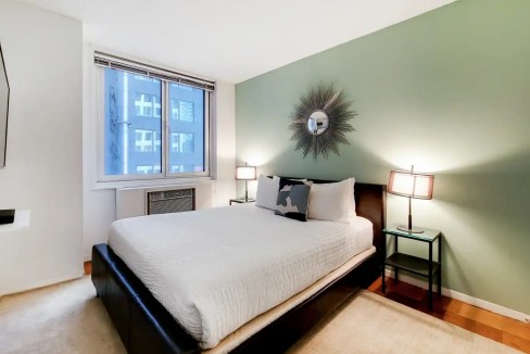 Comfortable bedroom with stylish decor at Broadway Theatre Apartments. Bright space featuring contem.