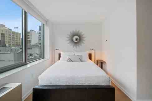 Bright, minimalist bedroom with large windows and city views at The High Line Galleries Apartments.