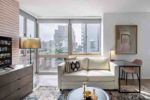 Modern living room with city views at Chelsea 6th Avenue Apartments.