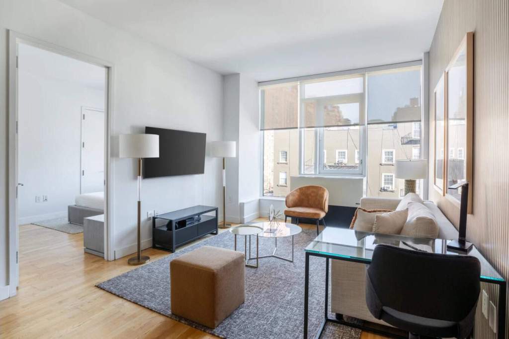 Bright living room in Chelsea Galleries Apartments with large windows and contemporary decor.