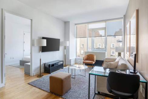 Bright living room in Chelsea Galleries Apartments with large windows and contemporary decor.