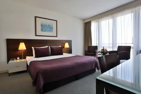 Ujlipotvaros aparthotel room with modern decor, large window, and cozy bedding in Budapest.