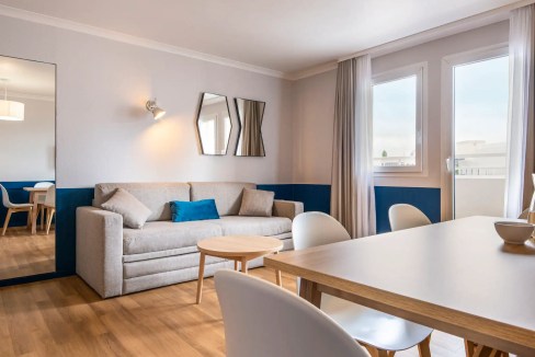 Bright living room with sofa, dining area, and large windows at La Defense Arena Aparthotel.