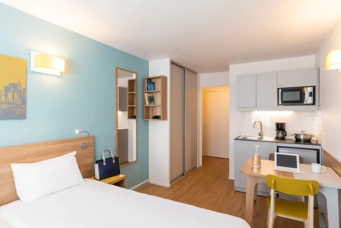 Cozy apartment room in Paris with bed, kitchenette, and workspace for travelers.