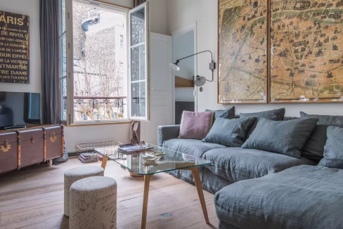 Bright lounge in Saint-Germain apartment with open French windows and blue sofas