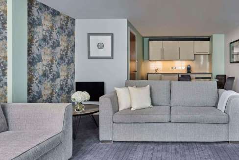 Comfortable living room in Glasgow Aparthotel featuring modern sofas, elegant wall art, and cozy amb.