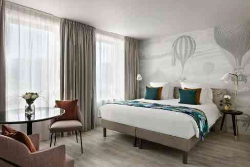 Spacious hotel room at Nantes Reze Centre Aparthotel featuring contemporary decor and large windows.
