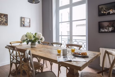 Dining area with rustic table and white walls in central Le Marais townhouse