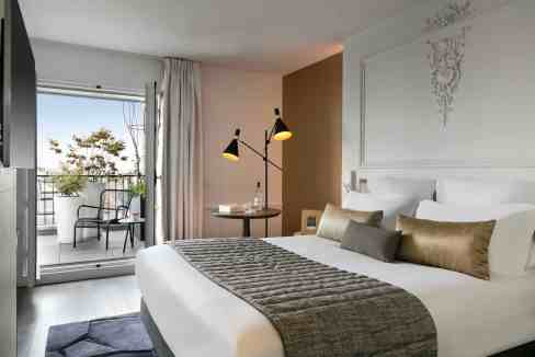 Hotel room with balcony overlooking Paris landmarks and cityscape.