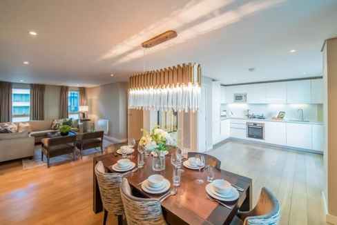 Modern living and dining area with stylish furniture, bright lighting, and open-plan kitchen in Merc.