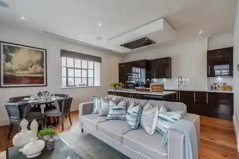 Living room with contemporary furniture and open kitchen at Palace Wharf Extended Stay Apartments.