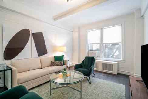 Bright living room with sofa, armchair, and artwork at Theodore Roosevelt Park Apartments.