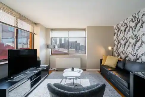 Interior view of a contemporary living room with large windows and cityscape in the background.