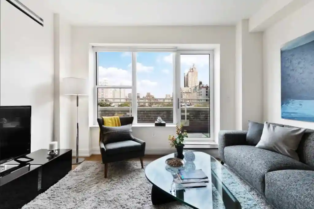 Bright living room in Central Park Apartments with large windows and city skyline backdrop.