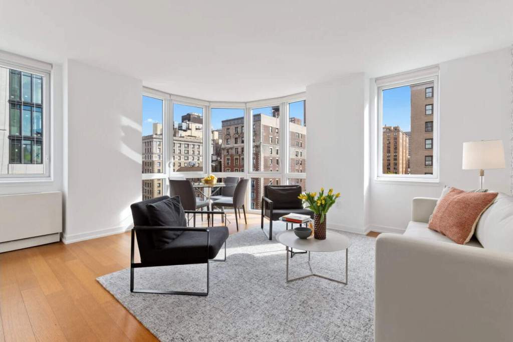 Bright living room with large windows showcasing cityscape views at Broadway Avenue Apartments.