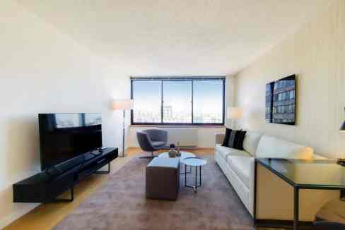 Stylish living room with contemporary furniture and large window overlooking Monterey Garden Apartme.