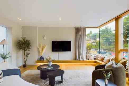 Living room with large windows overlooking the canal, modern furniture, and cozy decor.