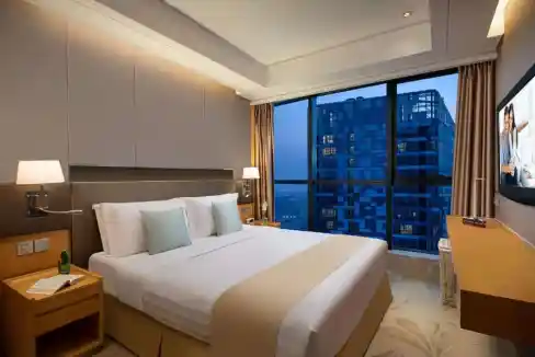 Comfortable hotel room at Beijing Dongzhimen Aparthotel with large windows and cityscape view.