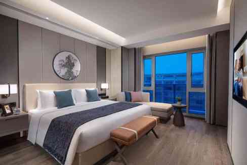 Elegant hotel room with contemporary furnishings and large window overlooking Beijing skyline.