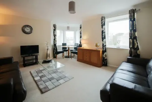 Bright and spacious living room with large windows and stylish decor at Aberdeen Great Western Apart.