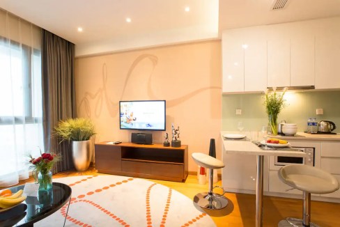 Modern Wuxi Xinwu District Aparthotel living room with TV, kitchen, and stylish furnishings.